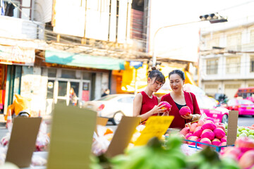 Wall Mural - Happy Asian family celebration Chinese Lunar New Year festival together. Mother and daughter choosing and buying fresh fruit orange for celebrating Chinese New Year at Chinatown street market.