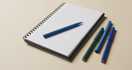 Canvas Print - Close up of notebook with blue markers on beige background, in slow motion