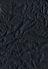 Dark crumpled paper texture. Minimalistic background. Charcoal paper backdrop. Noir cardstock pattern. Enigmatic textured backdrop. Deep matte black paper.