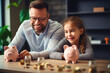 © FutureStock - Happy daughter and father putting coins to piggybanks while sitting at table at home.