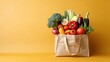 Healthy food selection. a Shopping bags full of fresh vegetables and fruits. Food lying flat on the table, orange color background, a lot of copy space