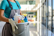 Close up of a cleaning woman holding a bucket filled with chemicals in modern building.