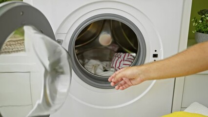 Wall Mural - Close-up of a person's hand holding a detergent pod while doing laundry in a modern washing machine inside a clean room.