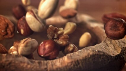 Canvas Print - Different nuts fall into a wooden bowl. Filmed on a high-speed camera at 1000 fps. High quality FullHD footage