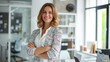 © venusvi - Confident businesswoman standing in office. Smiling woman standing with her arms crossed