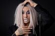 Guy in blonde wig posing like fashion model, pretend to be homosexual, transvestite, gay, lgbtq member. beauty industry, fashion, style. feminine male model with make-up on face isolated om black