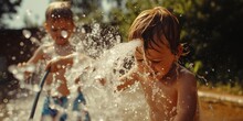 Two Young Boys Having Fun And Playing In A Sprinkle Of Water. Perfect For Summer Activities And Outdoor Play