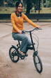 © ARMMY PICCA - Happy young Asian woman while riding a bicycle in a city park. She smiled using the bicycle of transportation. Environmentally friendly concept.