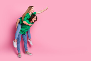 Poster - Full size profile side photo of couple teenagers playing together girl ride piggyback fist up to dream isolated on pink color background