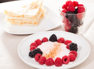 Wall Mural - Breakfast of raspberries and blackberries with yogurt and pancakes on table