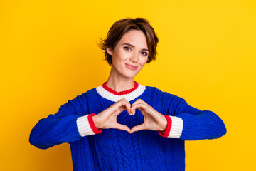 Sticker - Photo portrait of lovely young lady showing heart shape gesture wear trendy blue knitwear garment isolated on yellow color background