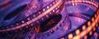 A close-up photograph of a spiral-shaped cinematic film reel, lit up with purple and orange lights.