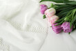 fresh tender pink-purple tulips on a light fabric background with lace. free space for inscription or text
