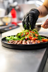 Wall Mural - chef hand cooking Roast beef salad with vegetables on restaurant kitchen