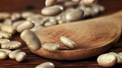 Poster - White beans fall on a wooden table. Filmed on a high-speed camera at 1000 fps. High quality FullHD footage