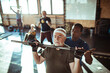 © Davor - Fitness instructor or trainer helping a group of seniors exercise and workout in the gym