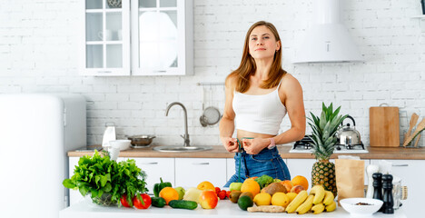 Canvas Print - Young woman standing in the kitchen with healthy food