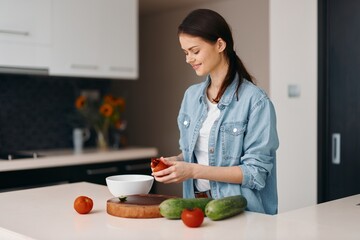 Wall Mural - Food, Health, and Happiness: A Beautiful Young Female Cook Preparing a Fresh Vegetarian Salad at Home.