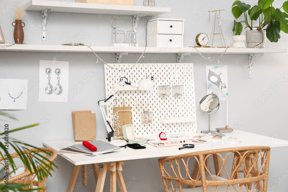 Sketches of stylish accessories with tools on jeweler table in workshop