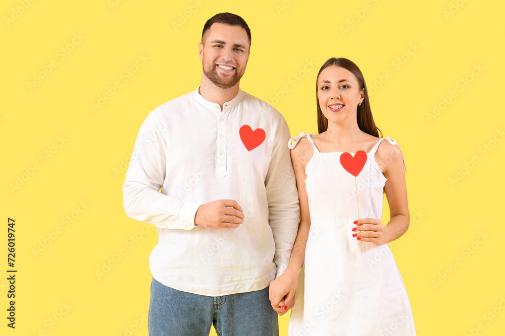 Lovely couple with paper hearts on yellow background. Valentine's Day celebration