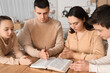 © Pixel-Shot - Family praying together with Holy Bible on table at home