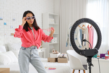 Wall Mural - Female Asian fashion blogger with sunglasses recording video in bedroom