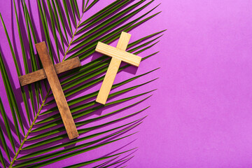 Wall Mural - Wooden crosses with palm leaf on purple background