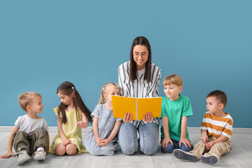 Sticker - Little children with nursery teacher reading book near blue wall