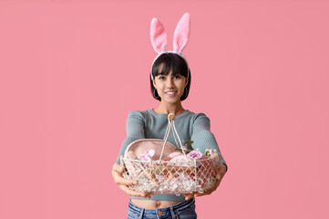 Canvas Print - Pretty young woman in bunny ears holding Easter basket with cosmetics on pink background