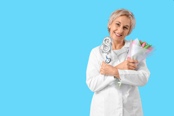 Canvas Print - Mature female doctor with tulips and figure 8 on blue background. International Women's Day celebration