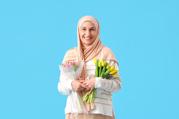 Poster - Mature Muslim woman with tulips on blue background. Ramadan celebration