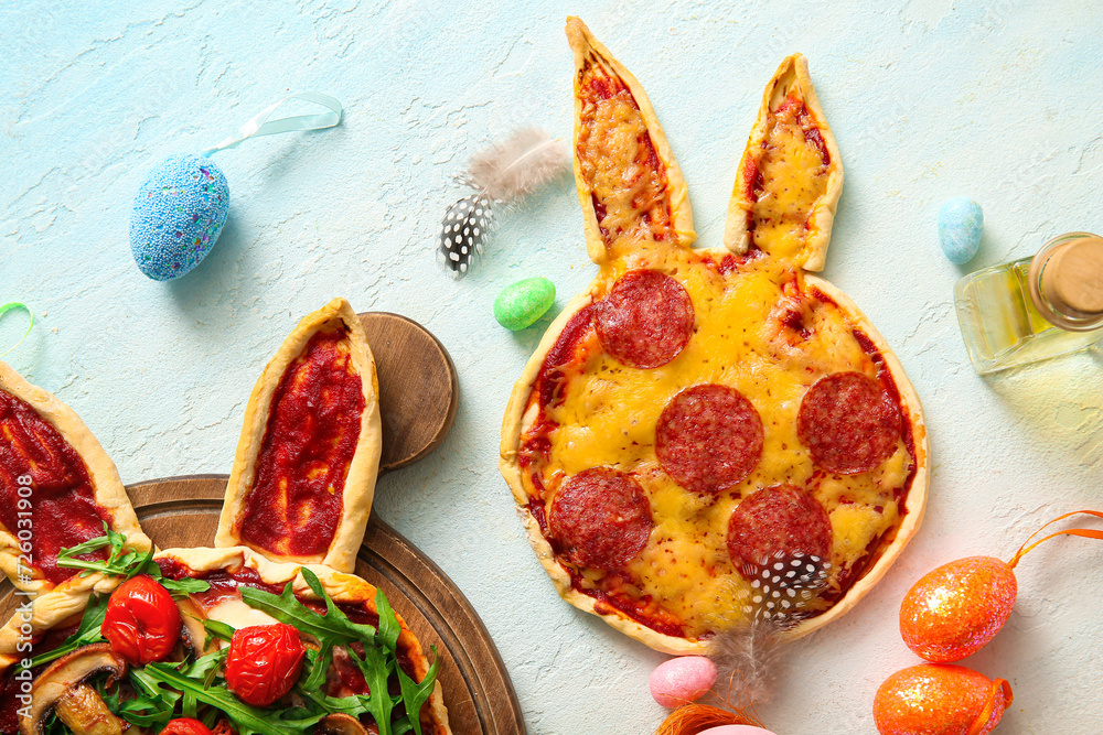 Composition with tasty pizzas and eggs for Easter celebration on blue background