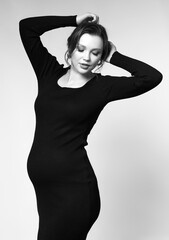 Wall Mural - Black and white portrait of pregnant female in black dress.