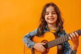 Fototapeta Uliczki - Evoke the spirit of music education with a delightful image of a child happily strumming a guitar against a flat orange backdrop. Ideal for advertising children's music programs.
