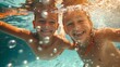 Photograph of siblings playing a game of tag underwater, with a burst of laughter and bubbles. 