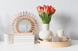 cozy spring home decorations setting with bouquet of red tulips, trendy mirror and candles