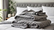Grey folded terry towels lie on clean white bed. Cleaning in guest room of hotel, cleanliness, laundry