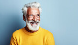 Fototapeta  - Joyful mature man with stylish white hair and beard, wearing a casual light sweater, radiating confidence and happiness on a light background