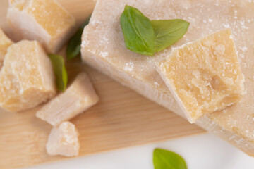 Wall Mural - Slices of parmesan cheese, close-up. grano padano cheese with fresh green basil leaves