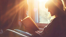 A Person Reading A Book In A Sunbeam With A Peaceful And Contented Smile.