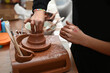 child's hand working clay to make pottery