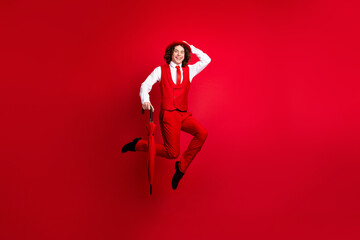 Poster - Full length body photo of funky guy jumping parasol touching his retro hat combination with vintage outfit isolated on red color background