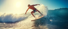 A Surfer Carves A Powerful Wave, Spray Flying, Embodying The Thrill Of Ocean Sports At Sunset