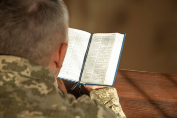 Wall Mural - Lifestyle portrait of Soldier in uniform reading Holy Bible. Natural aesthetic light