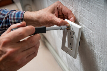 Installation or repair of electrical outlet socket box within the wall. Serviceman or repairman fixing with Type B Duplex Receptacle - American socket with grounding