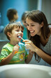 © Degimages - A family is in the bathroom, a mother shows her son how to brush his teeth, they both hold toothbrushes.
