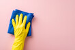Ideal for housekeeping tasks, this image showcases a hand in a rubber glove, effortlessly wiping with a microfiber cloth on a soft pink surface, leaving ample space for text or advertising