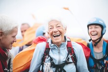 Senior Woman Laughing With Group Of Skydivers Holding Parachutes Prejump