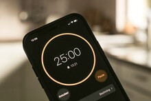 A phone with a black and white 25-minute timer to study with the pomodoro method on a blurry background. Perfect for students planning their time studying, doing homework, being productive.	