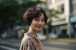 © wazamai - Stylish young Asian woman with short hair smiling on city street